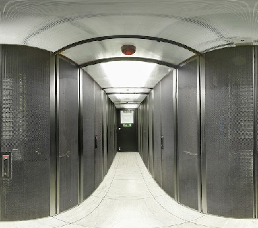 Photo of Machine Room, this photo depicts some of the University supercomputing infrastructure photographed with a camera lens which has made the servers in the racks appear curved. 